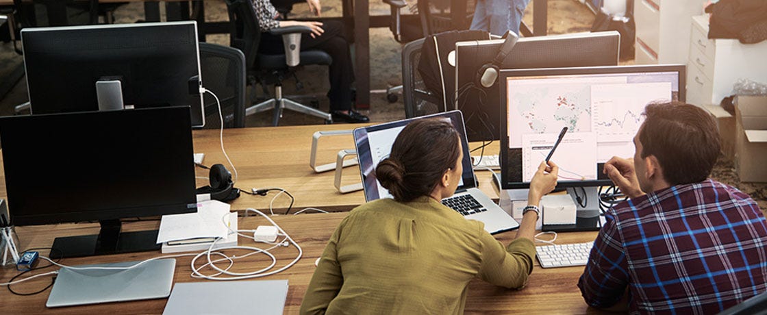 Two Co-workers collaborate on a project while sitting at a PC